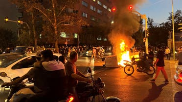 A picture obtained by AFP outside Iran shows demonstrators gathering around a burning barricade during a protest for Mahsa Amini, a woman who died after being arrested by the Islamic republic's morality police, in Tehran on September 19, 2022. (AFP)