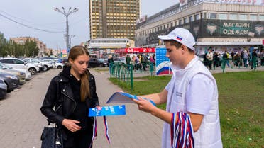 A volunteer of Luhansk regional election commission, right, distributes ribbons in colors of Russian national flag and posters reading Russia is the future, participate in the referendum! to local citizens prior to a referendum in Luhansk, Luhansk People's Republic controlled by Russia-backed separatists, eastern Ukraine, Thursday, Sept. 22, 2022. Authorities in Russian-controlled regions in eastern and southern Ukraine are preparing to hold referendums on becoming part of Russia's a move that could allow Moscow to escalate the war. The votes start Friday in the Luhansk, Kherson and partly Russian-controlled Zaporizhzhia and Donetsk regions. (AP Photo)
