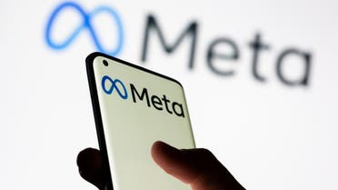 Woman holds smartphone with Meta logo in front of a displayed Facebook's new rebrand logo Meta in this illustration picture taken October 28, 2021. (Reuters)