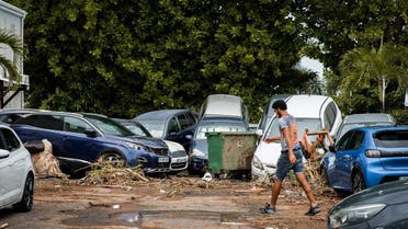 A pedestrian walks past cars overlapping each other and debris after the passage of Hurricane Fiona in Goyave, on the French island of Guadeloupe, on September 18, 2022. (AFP)
