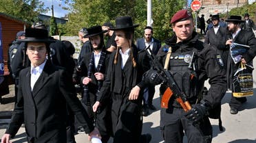 An armed police officer stays in guard as Hasidic Jewish pilgrims walk after pray at tomb of Rabbi Nachman for Rosh Hashana, the Jewish new year, in town of Uman, some 200km from Ukrainian capital of Kyiv on September 25, 2022. (AFP)