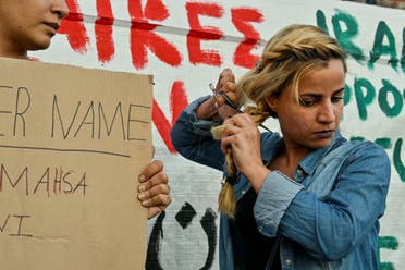 An Iranian refugee woman living in Greece cuts her hair during a demonstration by Iranians living in Greece in central Athens on September 24, 2022, following the death of an Iranian woman after her arrest by the country's morality police in Tehran. (AFP)