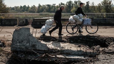  People walk on the destroyed bridge over the Oskil River as people evacuate from the recently retaken eastern bank in Kupiansk, Kharkiv region, on September 29, 2022. (AFP)