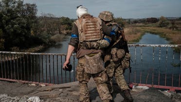 32KF7K9-A wounded Ukrainian serviceman crosses the bridge over the Oskil River in Kupiansk, in the recently retaken area near Kharkiv on September 30, 2022. (AFP)