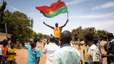 A man waves a Burkina Faso flag as others demonstrate while Burkina Faso soldiers are seen deployed in Ouagadougou on September 30, 2022. (AFP)