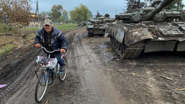 A local resident rides a bicycle past abandoned Russian tanks in the village of Kurylivka, amid Russia's attack on Ukraine, in Kharkiv region, Ukraine, on October 1, 2022.  (Reuters)