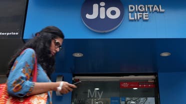 A woman checks her mobile phone as she walks past a mobile store of Reliance Industries' Jio telecoms unit, in Mumbai, India. (Reuters)