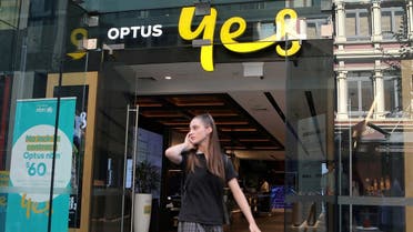 A woman uses her mobile phone as she walks past in front of an Optus shop in Sydney, Australia. (File photo: Reuters)