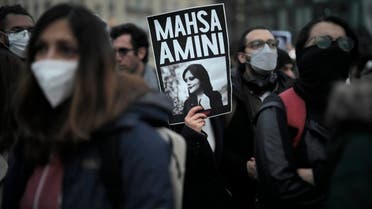 FILE - A woman shows a placard with a photo of of Iranian Mahsa Amini as she attends a protest against her death, in Berlin, Germany, Wednesday, Sept. 28, 2022. Amini's death in custody has sparked a stunning wave of protests across Iran, with women removing headscarves. A cousin, Irfan Mortezai, says the family is proud that Amini has become a symbol of resistance, but they are lying low out of worries over Iranian security agents. (AP Photo/Markus Schreiber, File)