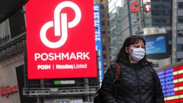 A woman walks through Times Square as a screen displays the company logo for Poshmark Inc. during its IPO at the Nasdaq Market Site in Times Square in New York City, US, on January 14, 2021. (Reuters)