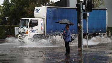 A pedestrian stands on the corner of a flooded street as heavy rains affect Sydney, Australia, October 6, 2022. (Reuters)