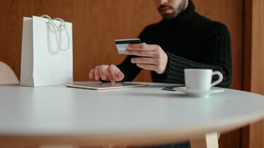 Stock image of a young man shopping online using his tablet and his credit card in a café. (Pexel, Cup of Couple)