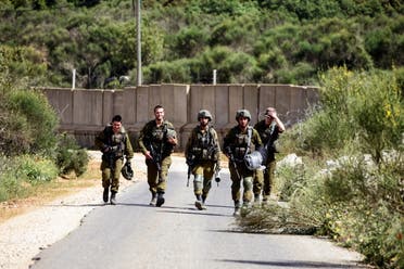 Israeli soldiers walk next to the Israel-Lebanon border near Shtula in northern Israel April 25, 2022. (Reuters) 