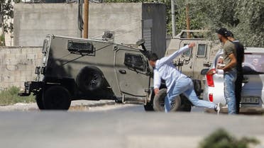 A Palestinian hurls a stone at an Israeli army vehicle during clashes after Israeli forces killed Palestinian gunmen in a raid, in Jenin in the Israeli-occupied West Bank September 28, 2022. REUTERS/Raneen Sawafta