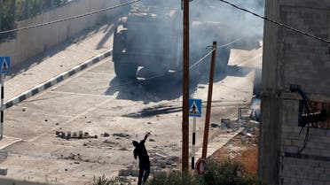 A Palestinian youth hurls stones toward Israeli military vehicles in the West Bank village of Deir al-Hatab east of Nablus, during ongoing clashes between Palestinian gunmen and Israeli troops, on October 5, 2022. (AFP)