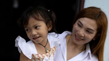 Panompai Sithong holds her 3-year-old daughter Paveenut Supolwong, nicknamed Ammy, who is the only child survivor of the day care center mass shooting, during a family meeting at their home in Uthai Sawan, Nong Bua Lam Phu province, Thailand, on October 9, 2022. (Reuters) 