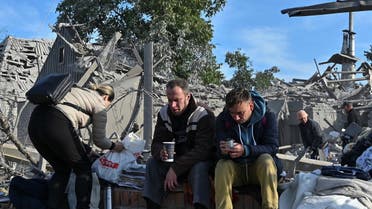 Distressed local residents sit at a site of a residential area heavily damaged by a Russian missile strike, amid Russia's attack on Ukraine, in Zaporizhzhia, Ukraine, on October 9, 2022. (Reuters)