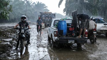 Residents leave their house under pouring rain at the former banana fields of the municipality of El Progreso, Yoro department, Honduras, before the arrival of Tropical Storm Julia,  October 8, 2022. (AFP)
