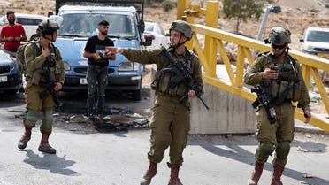 Israeli soldiers stand guard at one of the entrances of the Shuafat refugee camp in east Jerusalem on October 9, 2022, blocked traffic after an Israeli soldier was shot and killed in an overnight attack at a checkpoint near the camp. (AFP)