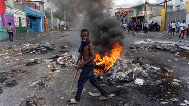 A mans walks past a burning barricade during a protest against Haitian Prime Minister Ariel Henry calling for his resignation, in Port-au-Prince, Haiti, October 10, 2022. Protests and looting have rocked the already unstable country since September 11, when Prime Minister Ariel Henry announced a fuel price hike. (Photo by Richard Pierrin / AFP)