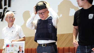 Robert Tsao (C), founder of Taiwanese microchip maker United Microelectronics Corporation (UMC), puts on a tactical helmet while wearing body armour during a press conference at the Parliament in Taipei on September 1, 2022. (File photo: AFP)