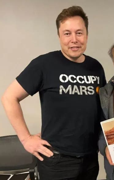 إيلون ماسك يرتدي قميص يحمل شعر احتلوا المريخ