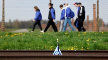 Young participants walk near a small national flag of Israel that has been placed at the rail tracks at the site of the former Auschwitz-Birkenau camp during commemorations to honor the victims of the Holocaust, near the village of Brzezinka near Oswiecim, Poland on April 28, 2022. (AFP)