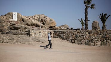 A man looks at his phone as he walks by a monument remembering the alleged genocide committed by German forces against Herero and Nama people in 1904, at Shark Island former concentration camp on June 26, 2017 in Luderitz, Namibia. (AFP)