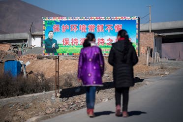 In this file photo taken on March 2, 2018, women walk past a propaganda poster showing China's President Xi Jinping next to a freeway outside of Qingshui, Qinghai province. (AFP)