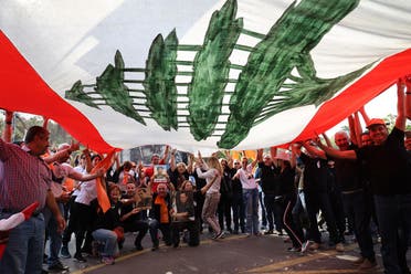 Supporters of Lebanon's President Michel Aoun cheer under a large national flag, as he prepares to leave the presidential palace in Babbda at the end of his mandate, east of the capital Beirut, on October 30, 2022. (AFP)