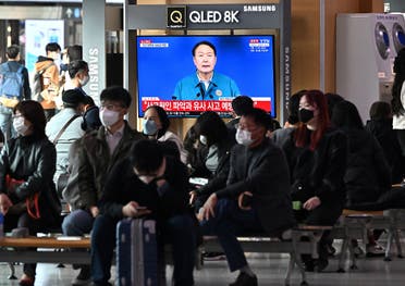 People watch a television news program broadcasting live footage of South Korean President Yoon Suk-yeol delivering a speech on the deadly Halloween stampede, at a railway station in Seoul on October 30, 2022. (AFP)