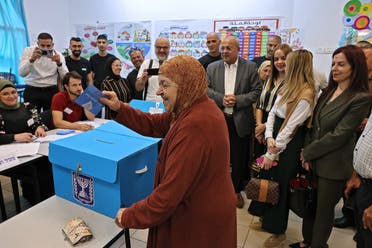 Ahmad Tibi (C-R), head of the Arab Movement for Change (Ta'al) party, stands behind a ballot box as he watches his mother (C) cast her ballot at a polling station in the predominantly-Arab city of Taybeh in central Israel during the national elections on November 1, 2022. (AFP)