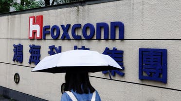 A woman carrying an umbrella walks past the logo of Foxconn outside a company's building in Taipei, Taiwan October 31, 2022. (File Photo: Reuters)