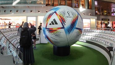 A traveller stands next to a giant football in the new central concourse building at the Hamad International Airport on November 10, 2022, in the Qatari capital Doha, ahead of the Qatar 2022 FIFA World Cup football tournament. (AFP)