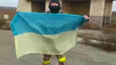 A serviceman in Klapaya village holds up the Ukrainian flag after Russia’s military said it had completed its withdrawal from Kherson. (Reuters)