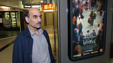 In this file photo taken on August 12, 2004 Mehran Karimi Nasseri passes by the poster of the movie inspired by his life, in the terminal 1 of Paris Charles De Gaulle airport. (AFP)