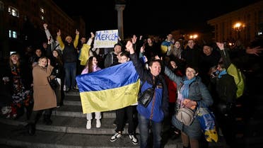 People hold a Ukranian flag and a slogan which reads as 11/11/2022 - Kherson - Ukraine as they gather in Maidan Square to celebrate the liberation of Kherson, in Kyiv on November 11, 2022, amid the Russian invasion of Ukraine. (AFP)