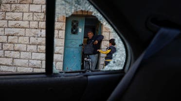 A Palestinian man holding a bike is seen through the damaged window of a car near the scene of an incident near Ramallah, in the Israeli-occupied West Bank November 14, 2022. (File photo: Reuters)