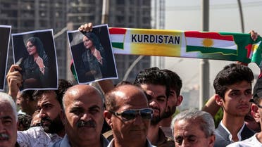 Men hold up signs depicting the image of 22-year-old Mahsa Amini, who died while in the custody of Iranian authorities, during a demonstration denouncing her death by Iraqi and Iranian Kurds outside the UN offices in Arbil, the capital of Iraq's autonomous Kurdistan region, on September 24, 2022. (AFP)