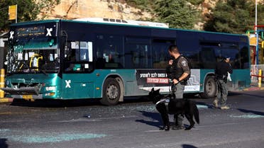 A police officer holds a dog next to a damaged bus following an explosion at a bus stop in Jerusalem November 23, 2022. (Reuters)