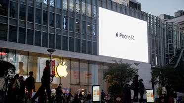 People walk near a display advertising the Apple iPhone 14 outside its store in Shanghai. (Reuters)