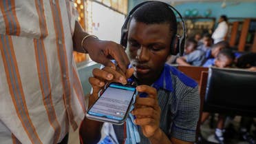A Vinsighte team member assists a visually impaired student with the Visis app, which aims at helping him read, at Pacelli School for the Blind and Partially Sighted Children, in Lagos, Nigeria, October 12, 2022. (Reuters)