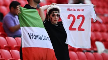 Iran fans hold a 'Women Life Freedom' Iran flag and a replica shirt in memory of Mahsa Amini, inside the stadium before the FIFA World Cup match between Iran and Wales match. (Reuters)