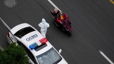 A man rides a vehicle carrying a woman past a police car outside a residential compound, during a lockdown to curb the spread of the coronavirus disease (COVID-19) in Shanghai, China April 5, 2022. Picture taken April 5, 2022. REUTERS/Aly Song
