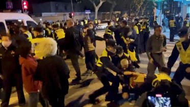 Police officers detain people during a protest against coronavirus disease (COVID-19) curbs at the site of a candlelight vigil for victims of the Urumqi fire, in Shanghai, China in this screengrab obtained from a video released on November 27, 2022. (Reuters)