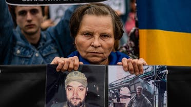A woman holds pictures of her son during a demonstration demanding to speed up the release from Russia authority of the Ukrainian prisoners involved in the battle of the Azovstal steel plant in Mariupol, downtown Kyiv, on October 1, 2022, amid the Russian military invasion of Ukraine. (AFP)