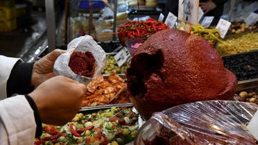 A shopkeeper scoops Tunisian Harissa to serve customers at the central market of the capital Tunis on December 1, 2022. (AFP)