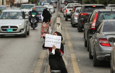 A beggar holds a sign reading My mother is sick with cancer, she needs chemotherapy in Sidon, Lebanon November 15, 2022. (Reuters)