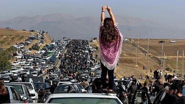 Una mujer sin velo de pie sobre un vehículo mientras miles se dirigen hacia el cementerio de Aichi en Saqez, la ciudad natal de Mahsa Amini, el 26 de octubre de 2022. (AFP)
