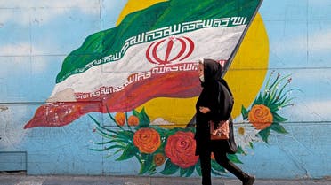 In this file photo taken on October 11, 2022, a woman walks past a mural in the Iranian capital Tehran. (AFP)
